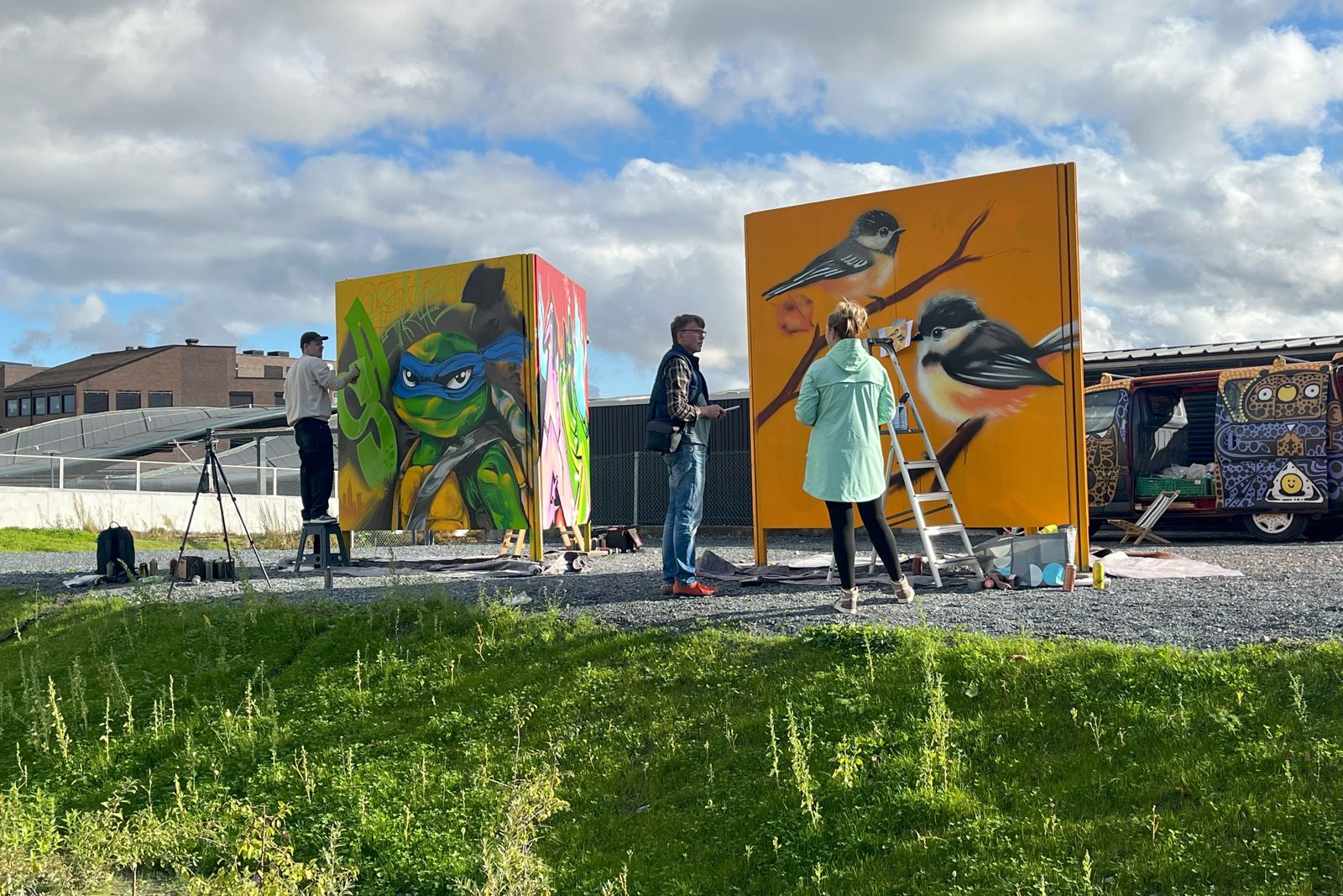 Tre mennesker som maler gatekunst i en park