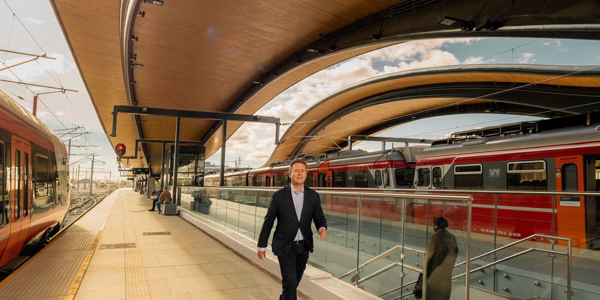 Mann går på nye Ski stasjon. Tog har stanset på begge sider av midtplattformen.